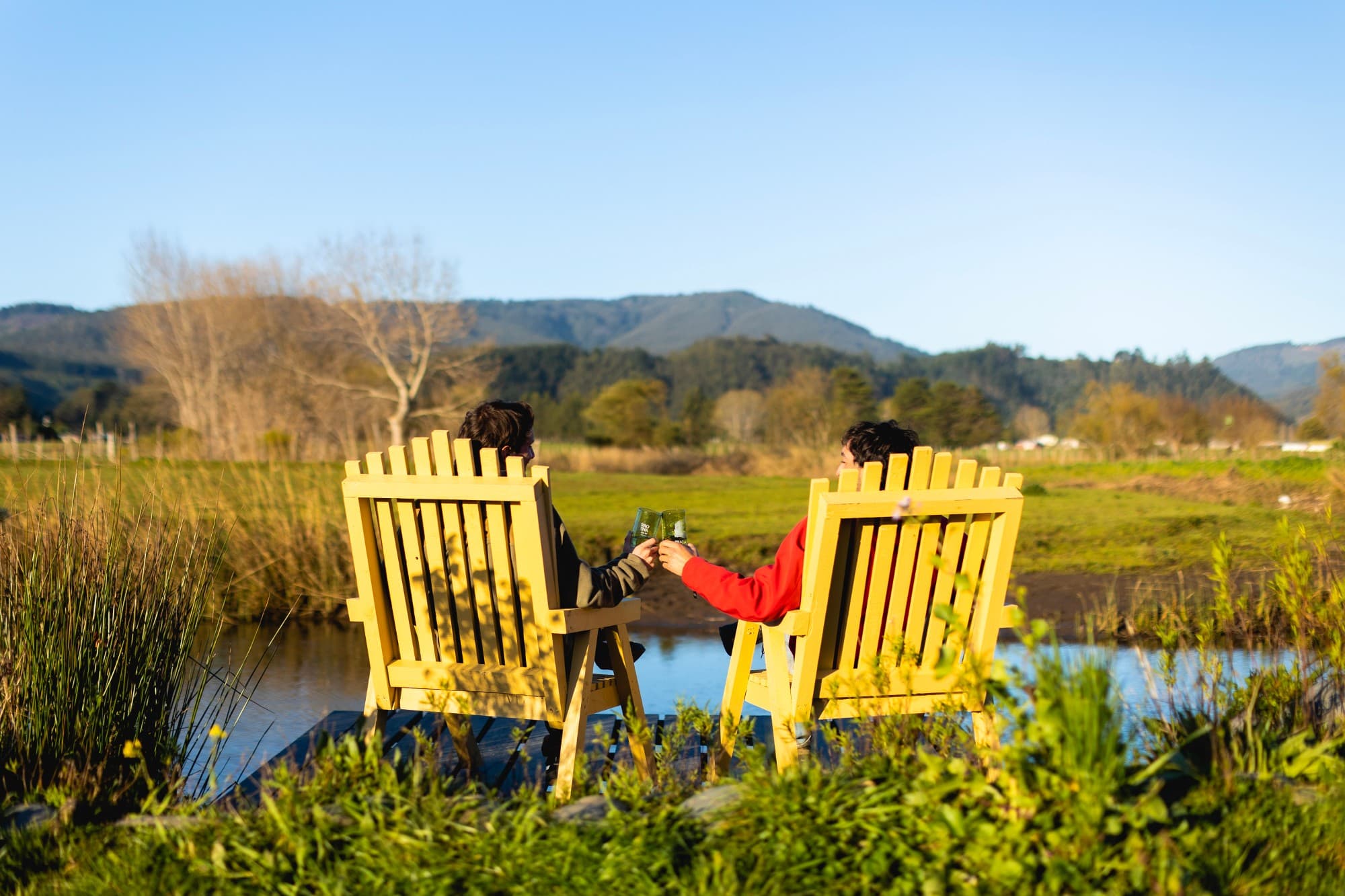 Amigos brindando junto al río, con la cordillera de fondo