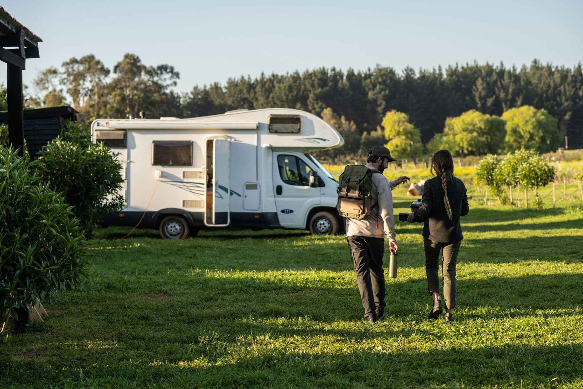 Pareja caminando hacia su motorhome, al atardecer